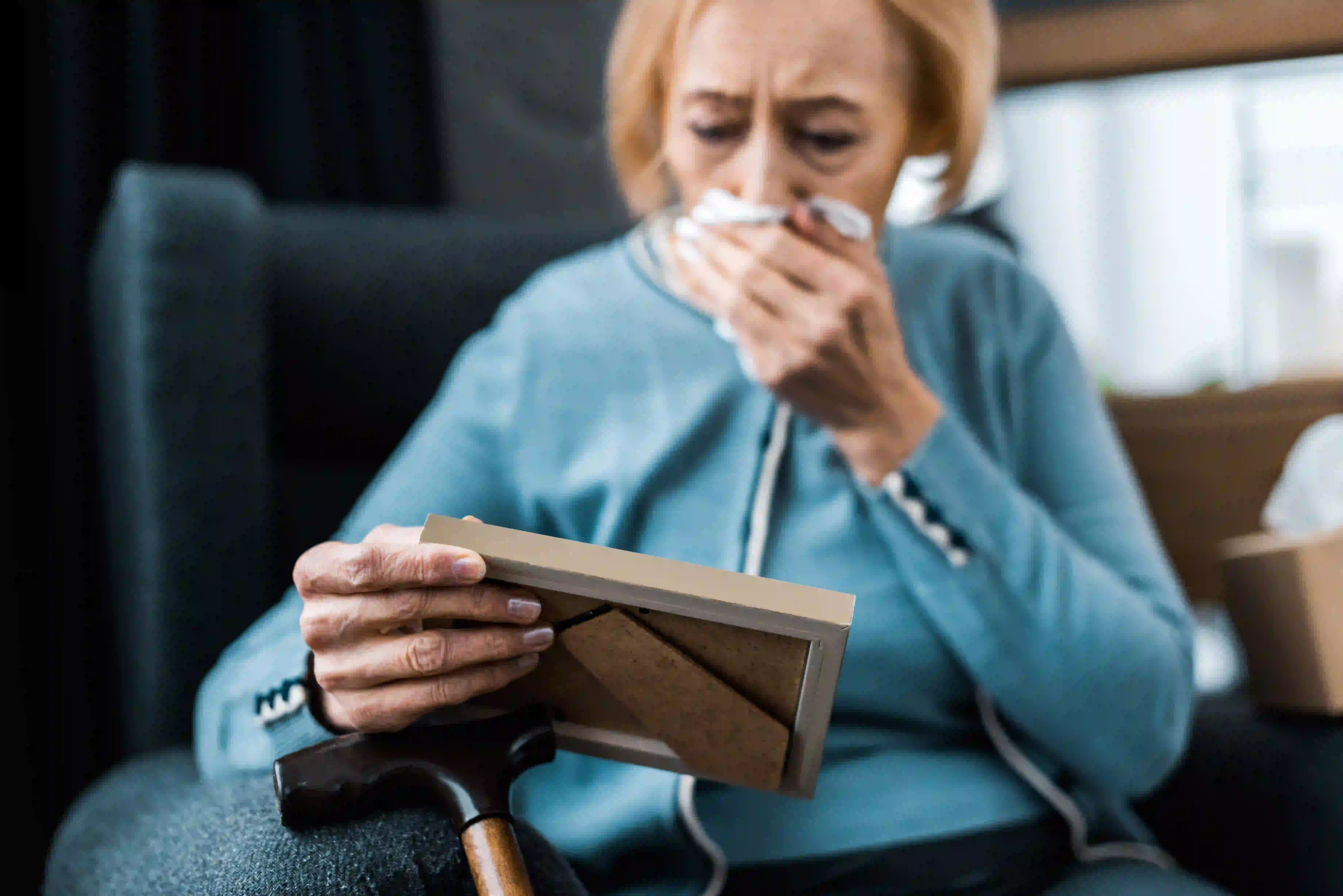 senior citizen woman crying while looking in a picture frame
