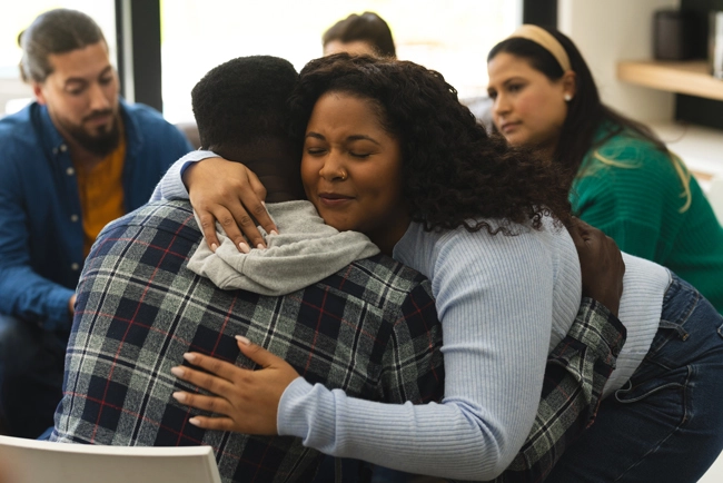 two african american male and female hugging in a support group session