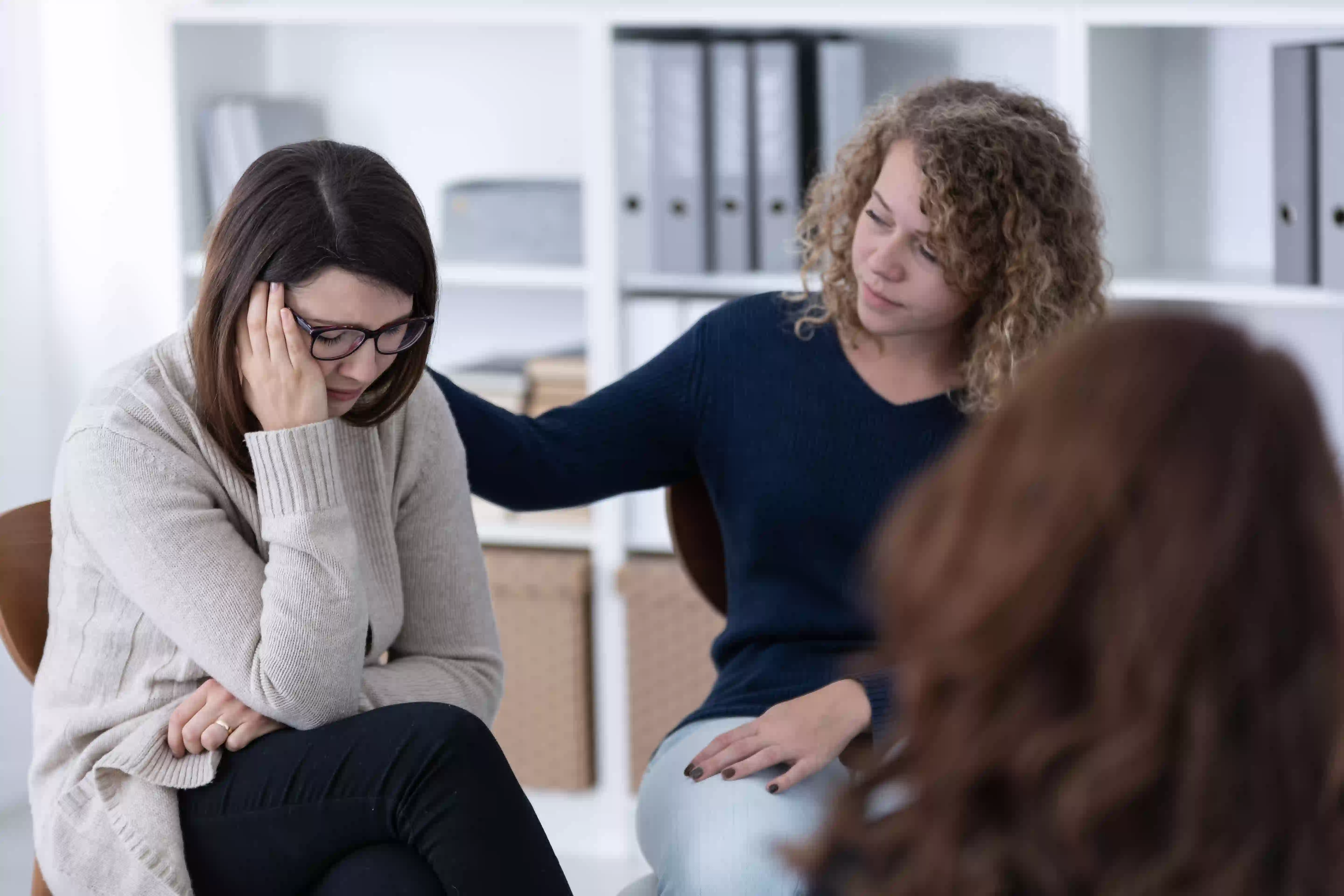 woman patting the back of another woman in a group session