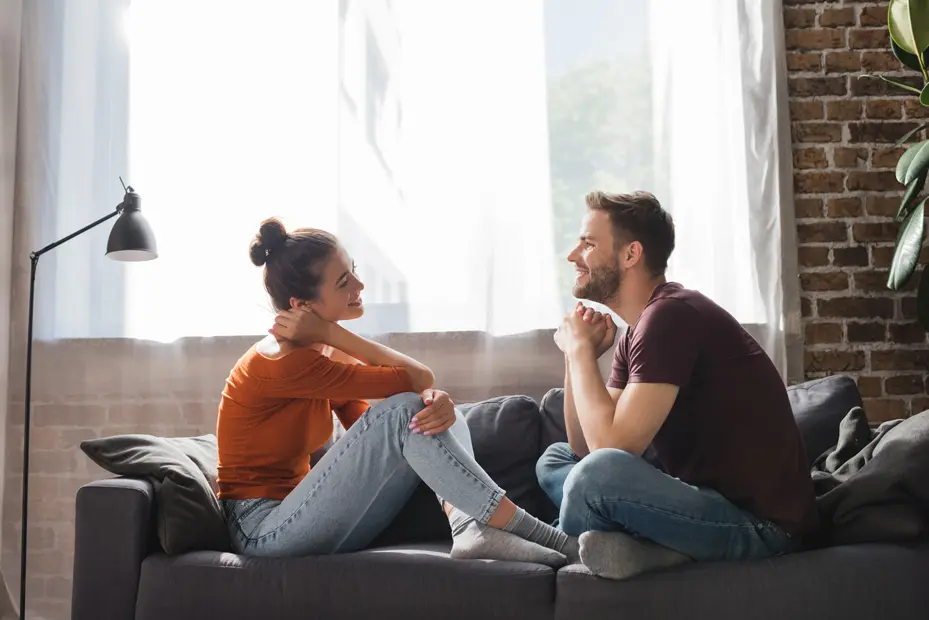 younger couple sitting in a couch smiling to each other