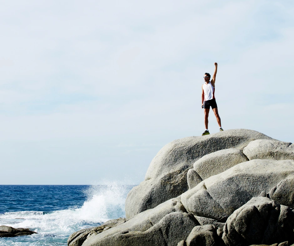 man standing on a big rock in the beach