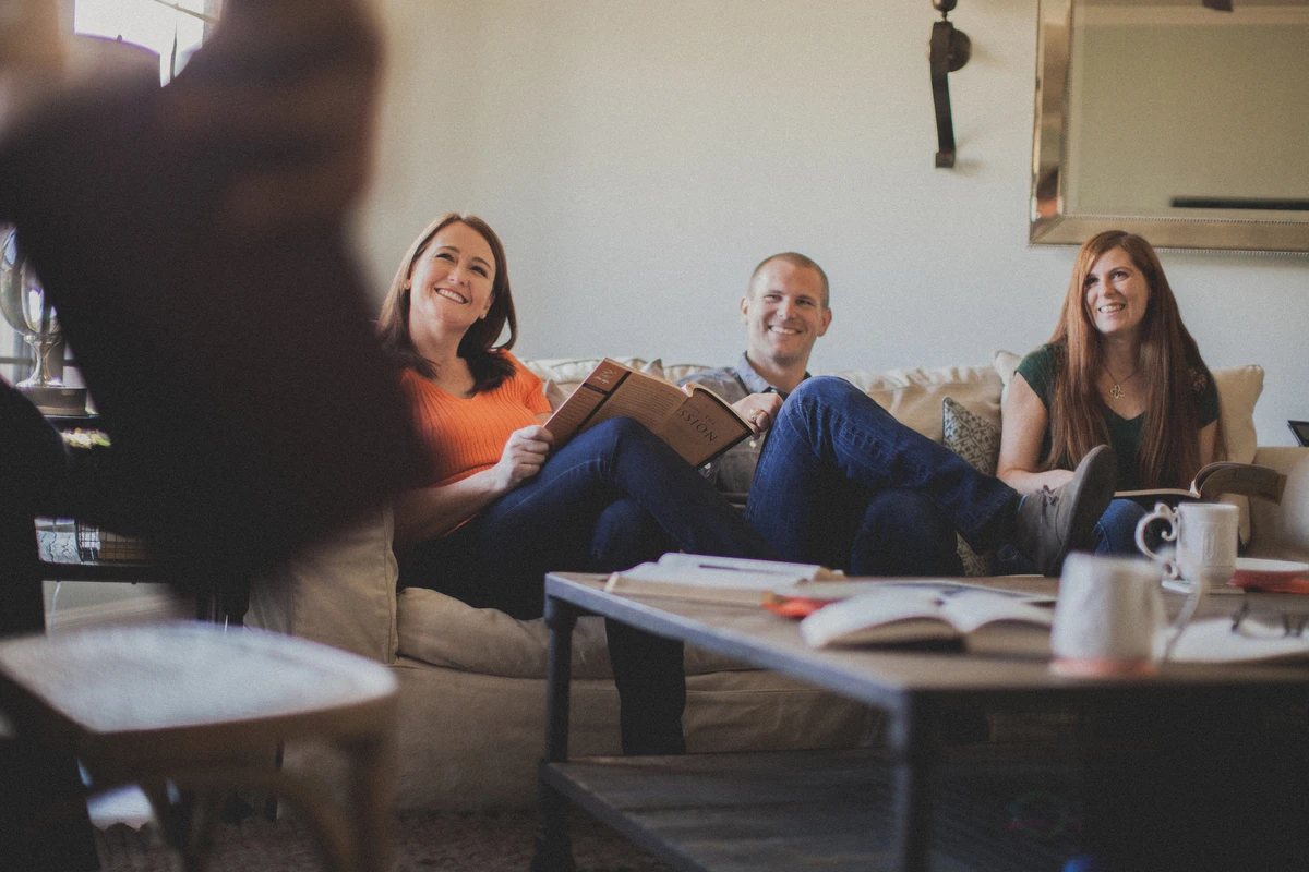 3 adults smiling while sitting