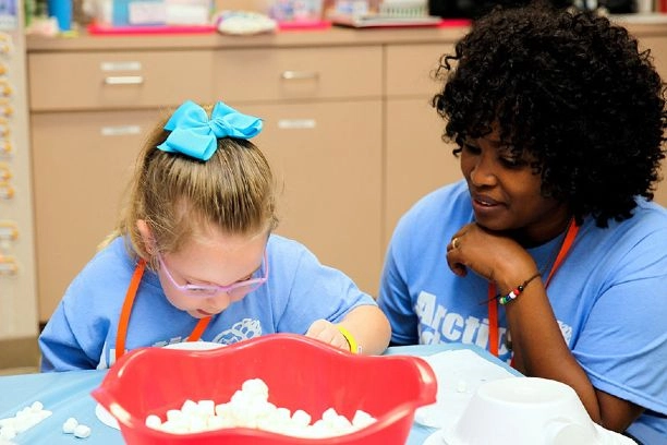 child painting with adult by her side