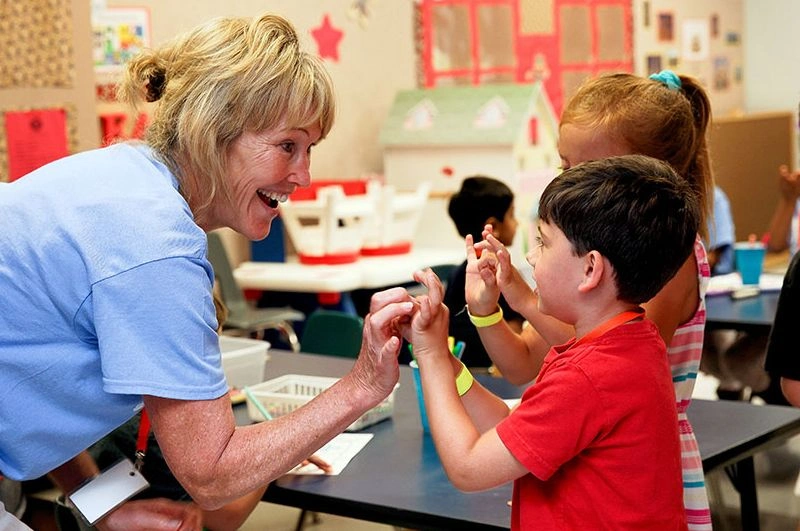 smiling woman shaking hands with children